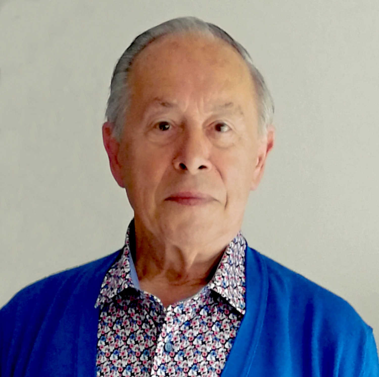 Portrait of Marc De Graeve in a blue cardigan against a pale background.
