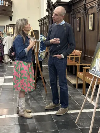 Two visitors in conversation beside artworks on display at Kunst in de Kerk